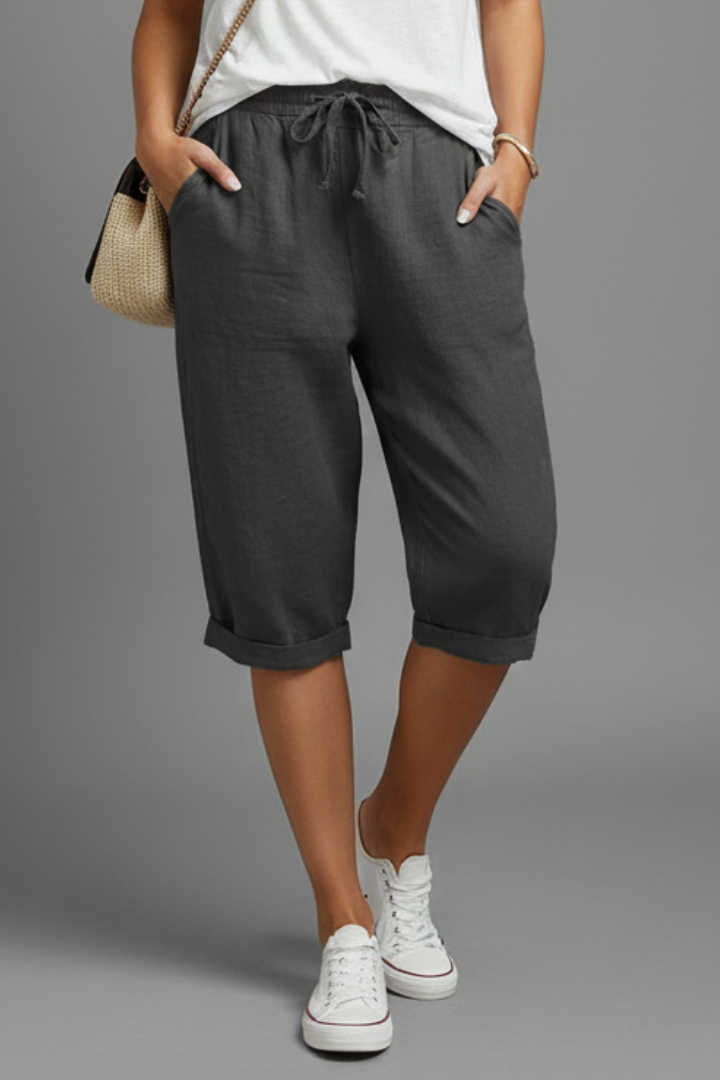 Beige women's knee-length trousers with high-waisted fit and straight legs, by THE WHITMORE FAMILY, displayed on a model.