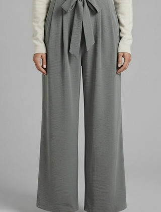 Beige women’s palazzo trousers with tie waist from THE WHITMORE FAMILY, shown lying flat on a light surface.