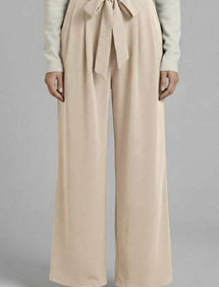 Beige women’s palazzo trousers with tie waist from THE WHITMORE FAMILY, featuring a relaxed fit and comfortable design.