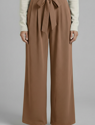 Beige women's palazzo trousers with tie waist from THE WHITMORE FAMILY, featuring a flowy fit and stylish design.