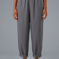 Beige women's trousers by THE WHITMORE FAMILY with an elastic waistband and side pockets, laid flat.