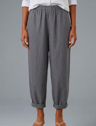 Beige women's trousers by THE WHITMORE FAMILY with an elastic waistband and side pockets, laid flat.