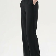 Women’s straight-leg trousers by THE WHITMORE FAMILY with pleated waist and side pockets, shown in a neutral color.