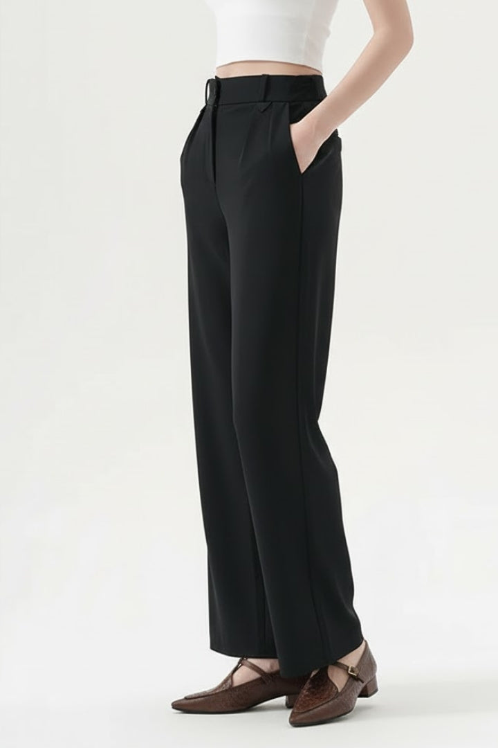 Women’s straight-leg trousers by THE WHITMORE FAMILY with pleated waist and side pockets, shown in a neutral color.