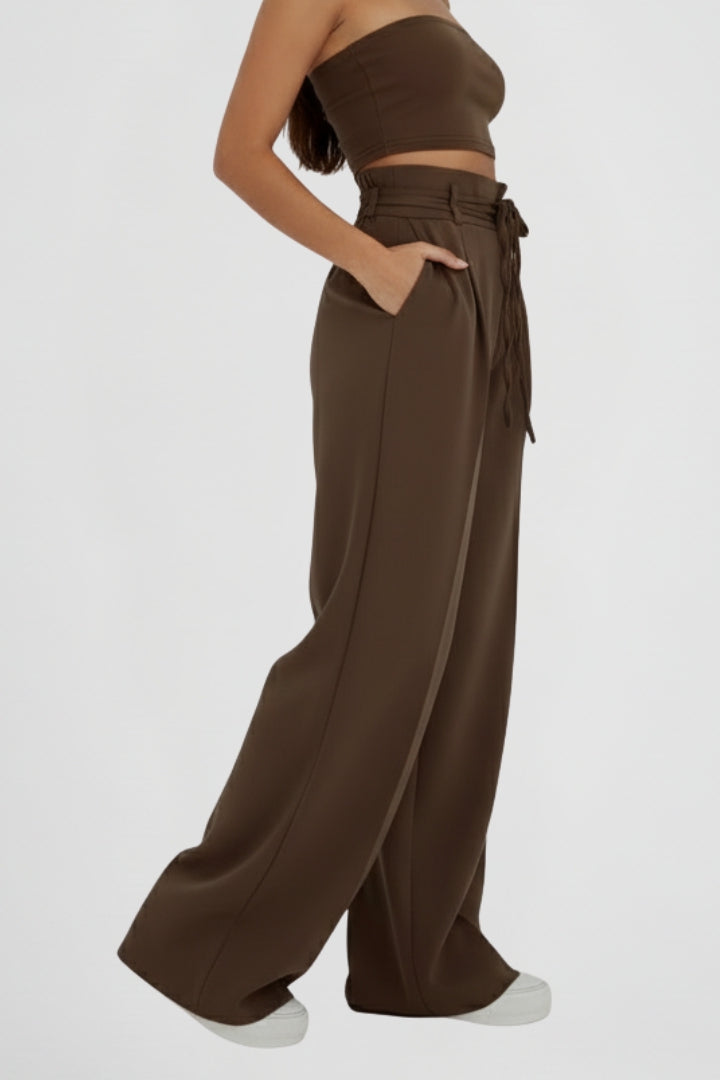 Women's wide leg trousers with tie waist and high rise from THE WHITMORE FAMILY, shown in a stylish, relaxed fit.