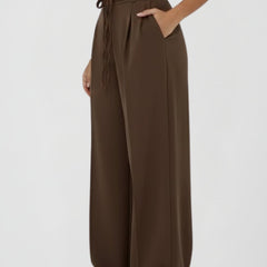 Women’s wide leg trousers with tie waist and high rise from THE WHITMORE FAMILY, showing the relaxed fit and stylish design.