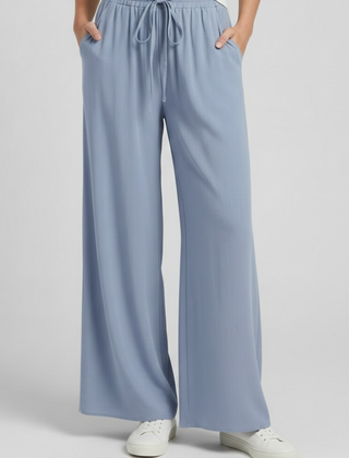Light blue women's palazzo trousers by THE WHITMORE FAMILY with drawstring waist and side pockets.