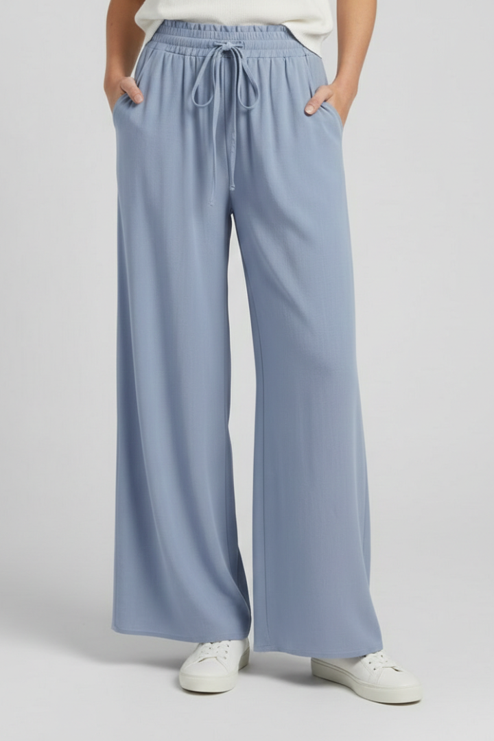 Light blue women's palazzo trousers by THE WHITMORE FAMILY with drawstring waist and side pockets.