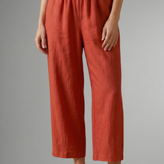 Women’s pink trousers with elastic waistband and wide legs by THE WHITMORE FAMILY, shown hanging on a hanger.