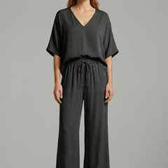 Women’s two-piece trousers set by THE WHITMORE FAMILY featuring a black design, V-neck top, and wide-leg pants.