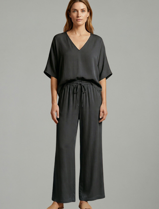 Women’s two-piece trousers set by THE WHITMORE FAMILY featuring a black design, V-neck top, and wide-leg pants.
