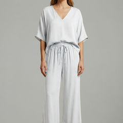 Women’s two-piece trousers set by THE WHITMORE FAMILY featuring a black V-neck top and wide-leg trousers.
