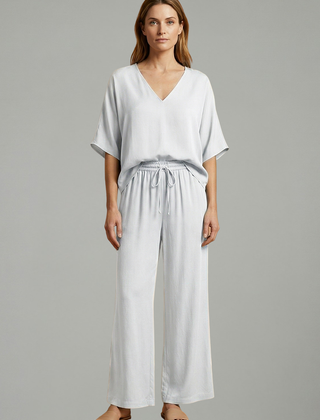 Women’s two-piece trousers set by THE WHITMORE FAMILY featuring a black V-neck top and wide-leg trousers.