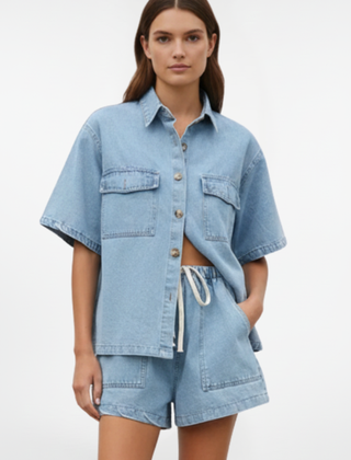 Women’s denim set by THE WHITMORE FAMILY featuring a short-sleeve shirt jacket and matching shorts in subtle blue denim.