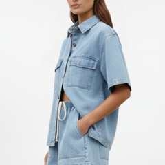 Women’s denim set by THE WHITMORE FAMILY featuring a short-sleeve shirt jacket and matching shorts, in subtle blue denim.