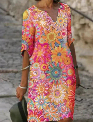 Nira vibrant floral midi dress by THE WHITMORE FAMILY, shown in yellow with a flowing silhouette and colorful floral pattern.