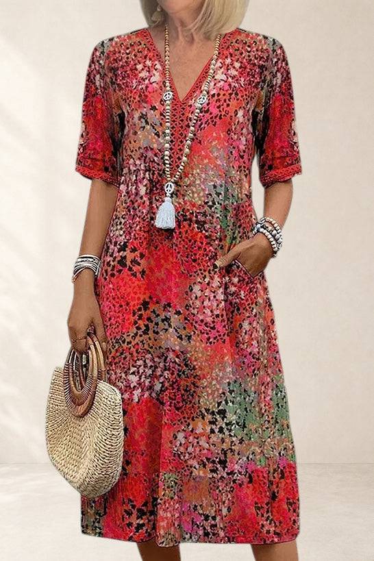 Red floral Veronica Vibrant Midi Dress by The Whitmore Family, shown on a model with a fitted waist and flowing skirt.